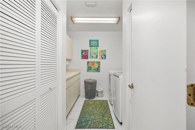 washroom with cabinets, light tile patterned floors, and washing machine and clothes dryer