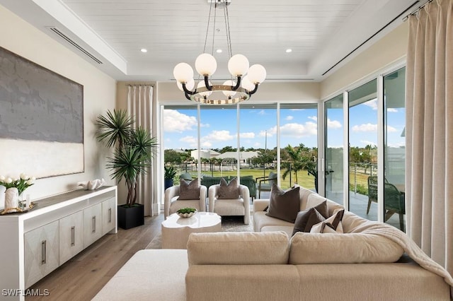 living room with wooden ceiling, light wood-type flooring, a tray ceiling, and a notable chandelier