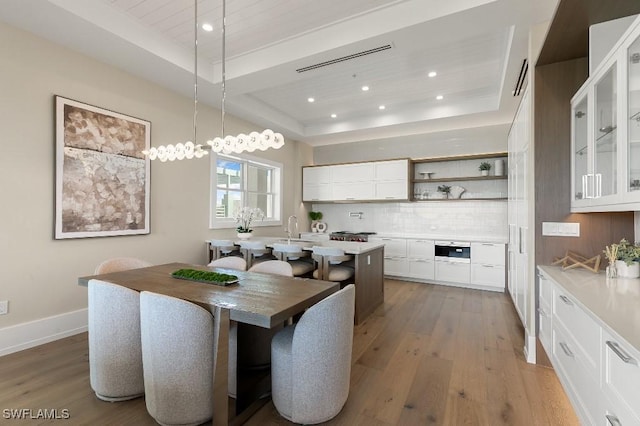 dining area featuring hardwood / wood-style floors, sink, and a tray ceiling