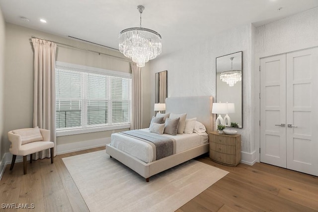 bedroom with light hardwood / wood-style floors and an inviting chandelier