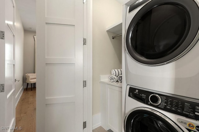 washroom with stacked washer / drying machine and light hardwood / wood-style flooring