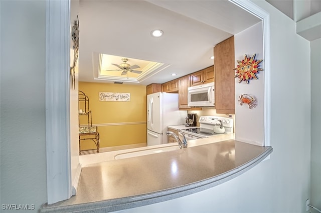 kitchen featuring ceiling fan, white appliances, sink, and a tray ceiling