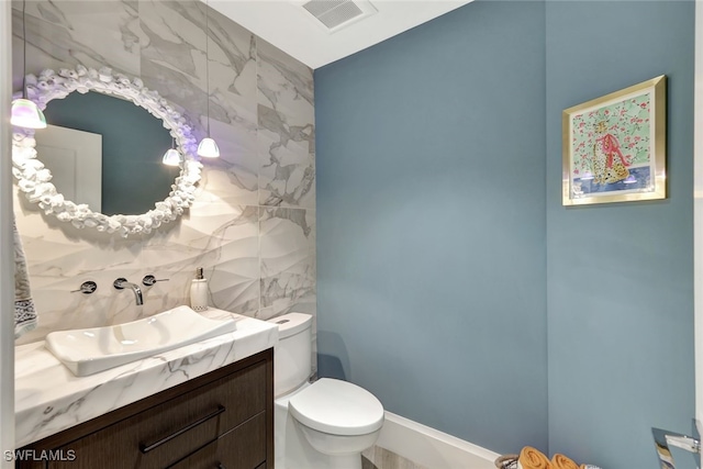 bathroom featuring toilet, vanity, and tile walls