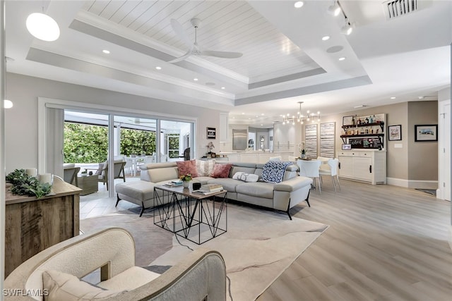 living room featuring light hardwood / wood-style floors, crown molding, ceiling fan with notable chandelier, and a raised ceiling