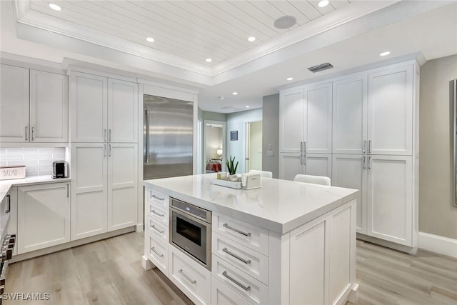 kitchen featuring appliances with stainless steel finishes, white cabinets, a tray ceiling, and backsplash