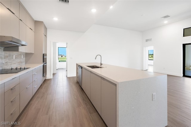 kitchen with sink, dishwasher, an island with sink, black electric cooktop, and decorative backsplash