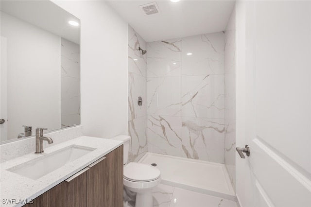 bathroom featuring vanity, toilet, and a tile shower