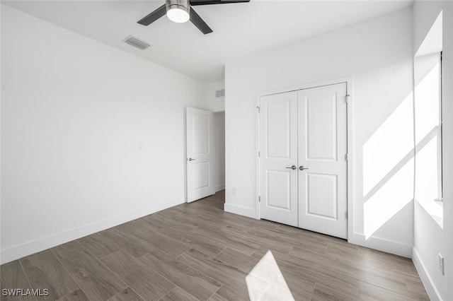 unfurnished bedroom with ceiling fan, a closet, and light hardwood / wood-style flooring