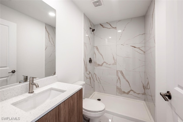 bathroom featuring tiled shower, vanity, and toilet