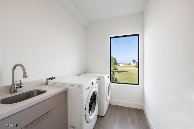 laundry area with sink, independent washer and dryer, and light wood-type flooring