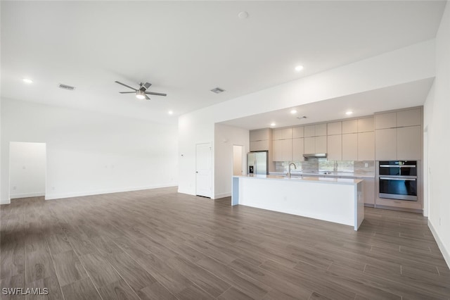 kitchen featuring a large island, sink, backsplash, stainless steel appliances, and dark hardwood / wood-style floors