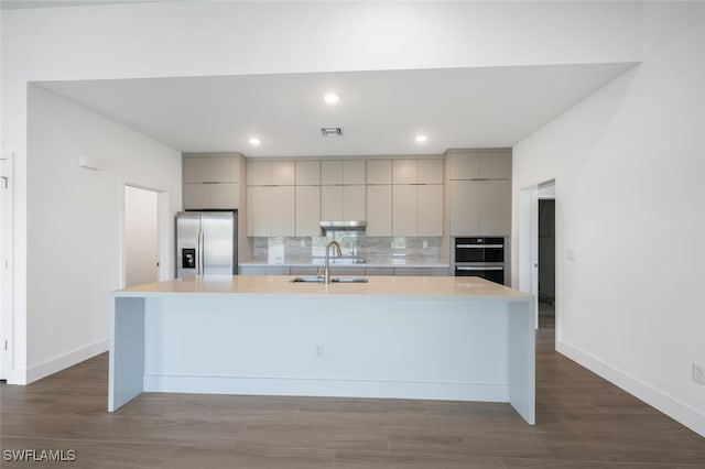 kitchen featuring sink, gray cabinetry, backsplash, stainless steel refrigerator with ice dispenser, and a spacious island