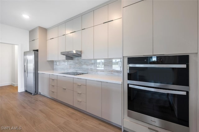 kitchen with light hardwood / wood-style flooring, black electric stovetop, double wall oven, stainless steel fridge with ice dispenser, and decorative backsplash