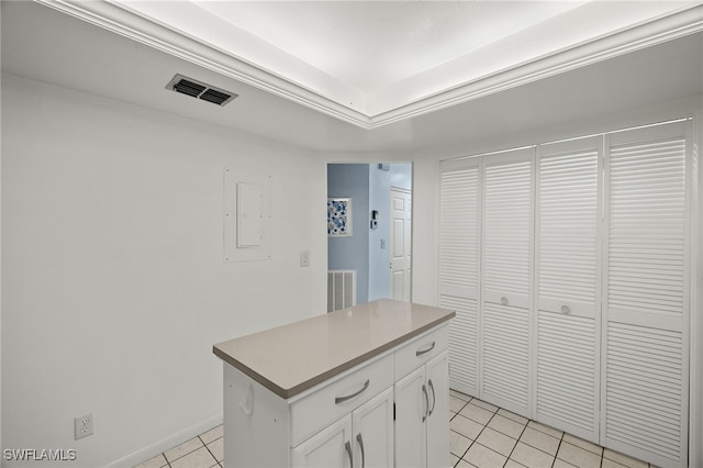 kitchen with light tile patterned floors, electric panel, ornamental molding, a kitchen island, and white cabinets