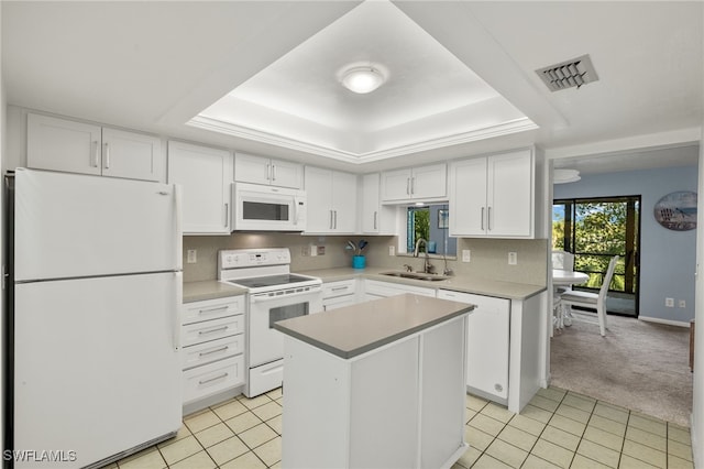 kitchen with sink, a center island, white appliances, a tray ceiling, and light colored carpet