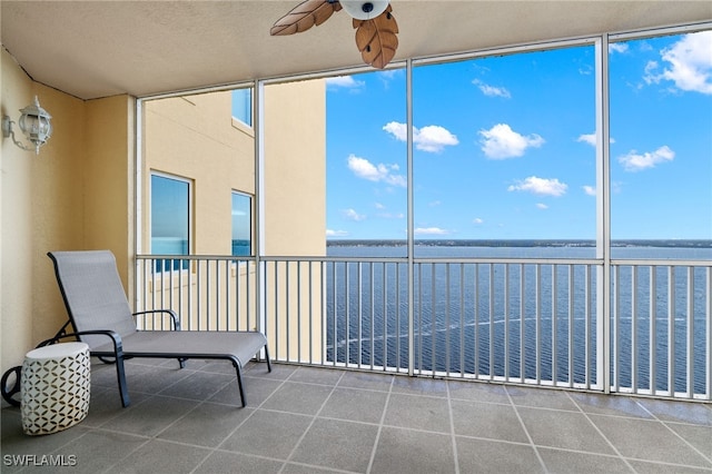 unfurnished sunroom with a water view and ceiling fan