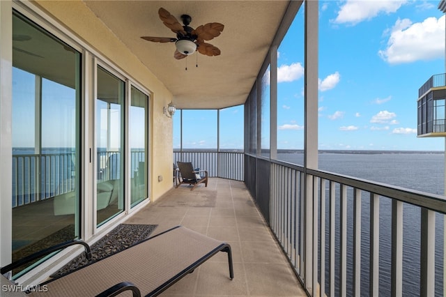 unfurnished sunroom featuring a water view, ceiling fan, and a healthy amount of sunlight