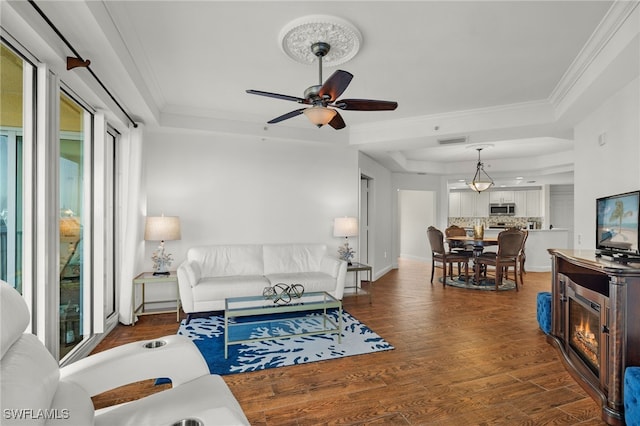 living room featuring a raised ceiling, plenty of natural light, and dark hardwood / wood-style flooring