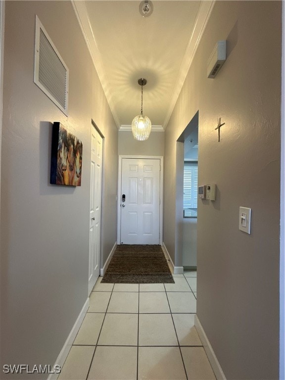 entryway with crown molding, an inviting chandelier, and light tile patterned floors