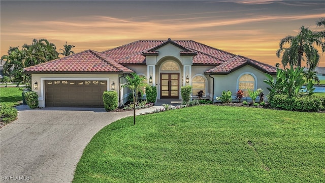 mediterranean / spanish-style house with a garage and a lawn