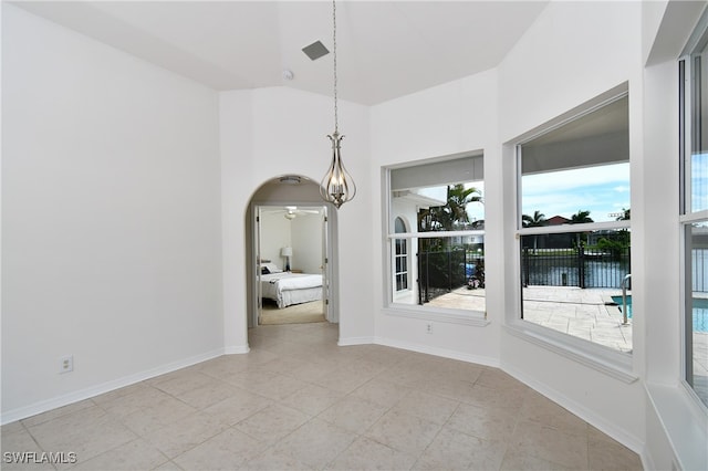 unfurnished dining area featuring a wealth of natural light, light tile patterned floors, a water view, and vaulted ceiling