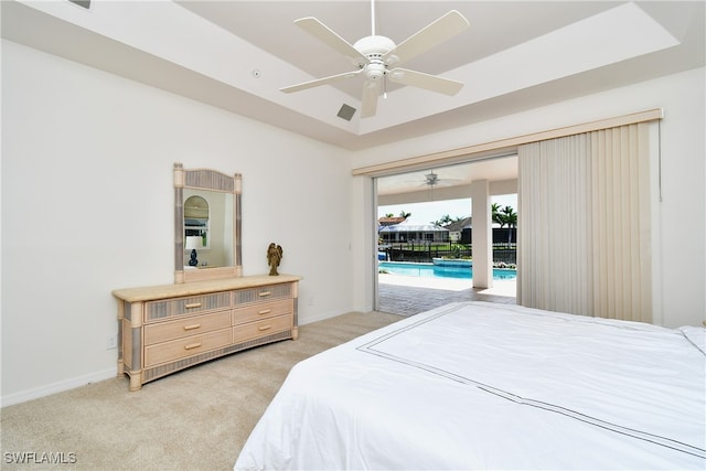 bedroom with access to outside, a tray ceiling, light colored carpet, and ceiling fan