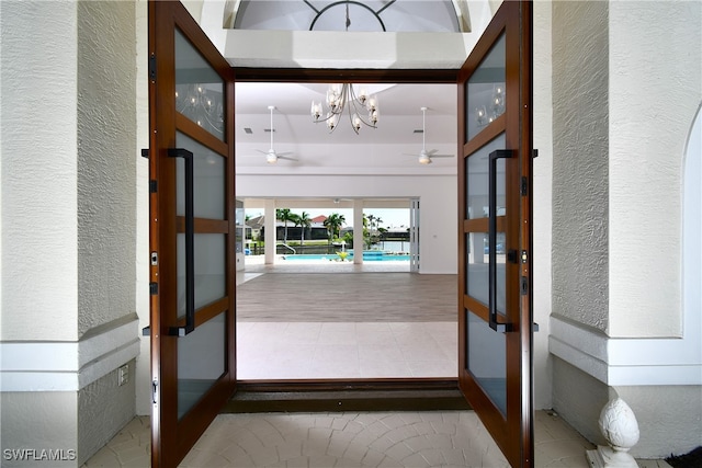 entryway featuring ceiling fan with notable chandelier and light hardwood / wood-style flooring