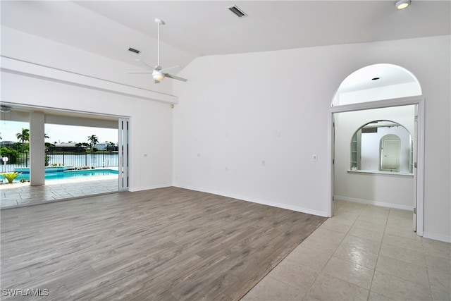 spare room featuring light wood-type flooring, lofted ceiling, and ceiling fan