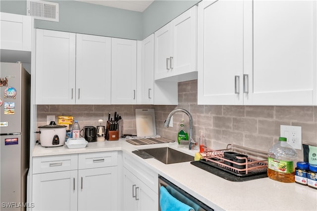 kitchen featuring decorative backsplash, white cabinets, stainless steel appliances, and sink