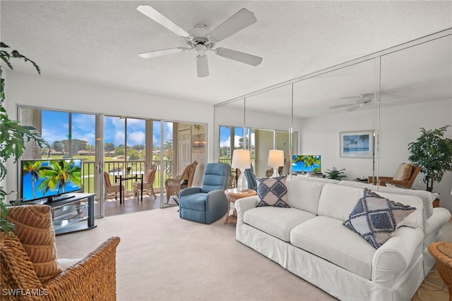 living room featuring ceiling fan, a textured ceiling, a healthy amount of sunlight, and carpet flooring