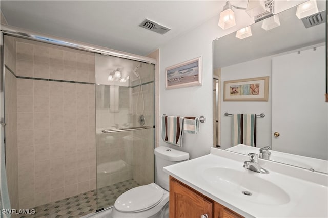 bathroom with a shower with door, vanity, and toilet