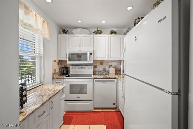 kitchen featuring white cabinets, light stone counters, backsplash, and white appliances