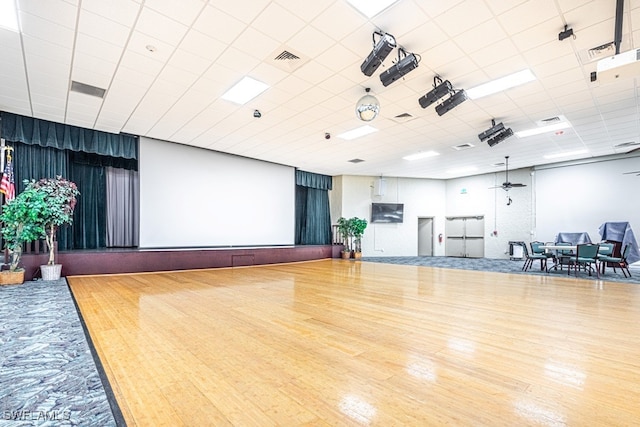 exercise room with a paneled ceiling, wood-type flooring, and ceiling fan