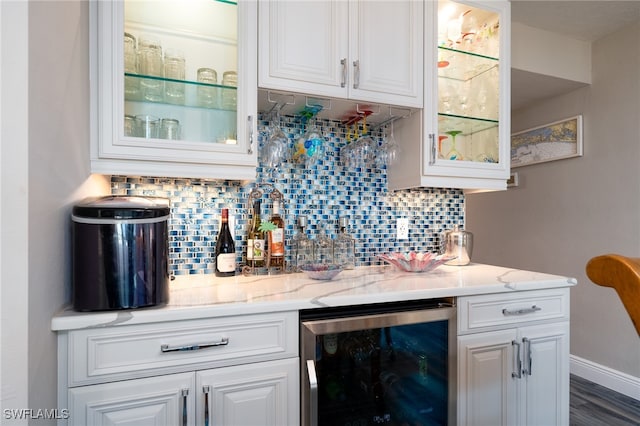 bar featuring backsplash, beverage cooler, white cabinetry, light stone counters, and dark hardwood / wood-style flooring