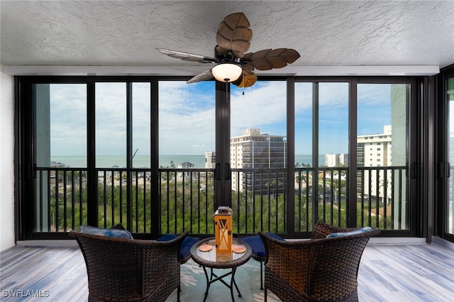 sunroom with a water view, ceiling fan, and a wealth of natural light