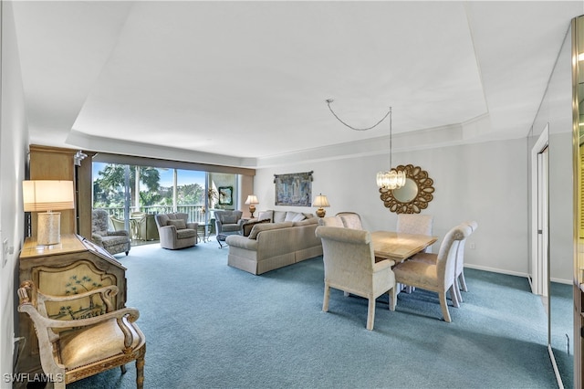 carpeted dining space with a notable chandelier and a raised ceiling