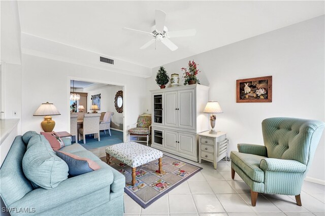 living room with ceiling fan with notable chandelier and light tile patterned floors