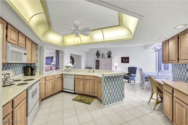 kitchen featuring decorative backsplash, kitchen peninsula, light tile patterned floors, white appliances, and ceiling fan