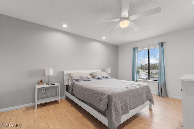 bedroom with a textured ceiling, light hardwood / wood-style flooring, and ceiling fan