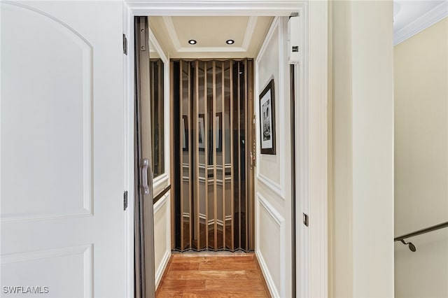 hallway with light hardwood / wood-style flooring and crown molding