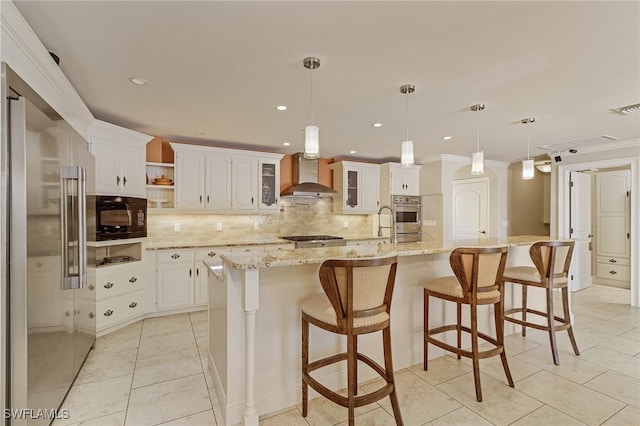 kitchen with white cabinets, a large island, wall chimney range hood, and appliances with stainless steel finishes