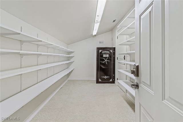 walk in closet featuring light colored carpet and lofted ceiling