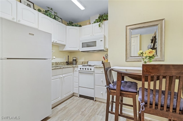 kitchen with light wood-type flooring, light stone counters, white appliances, sink, and white cabinetry