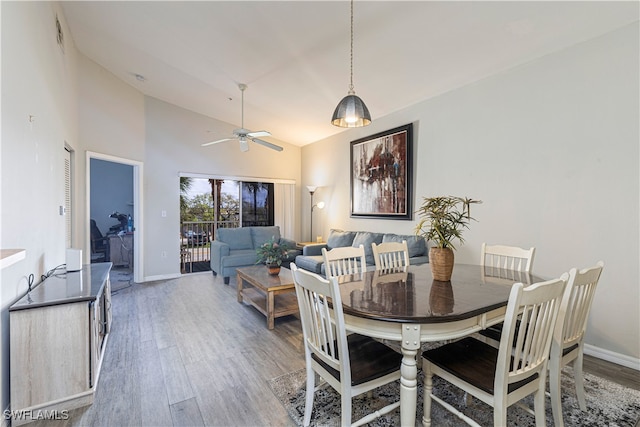 dining area with hardwood / wood-style flooring, ceiling fan, and high vaulted ceiling