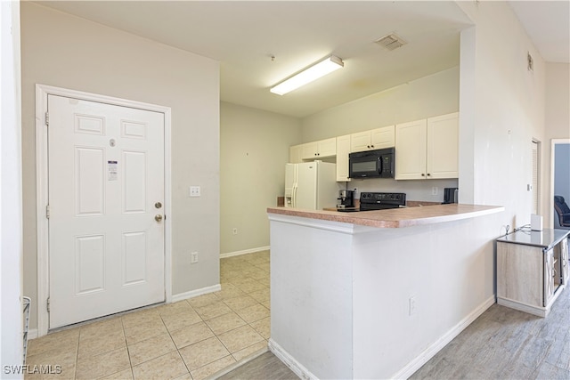 kitchen with white cabinets, black appliances, kitchen peninsula, and light wood-type flooring