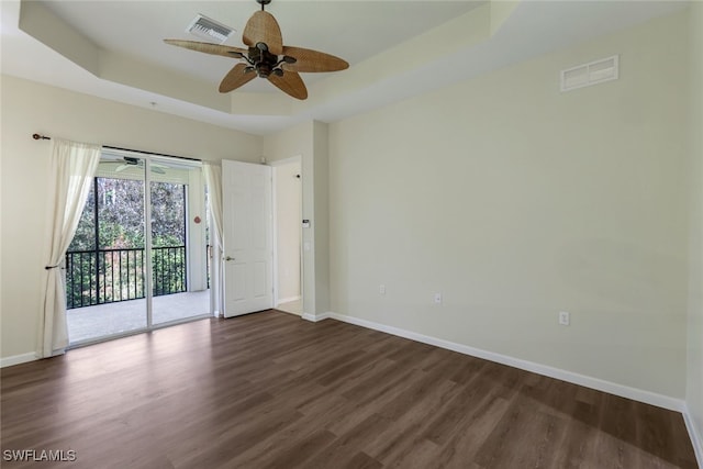 unfurnished room featuring dark hardwood / wood-style flooring, a tray ceiling, and ceiling fan