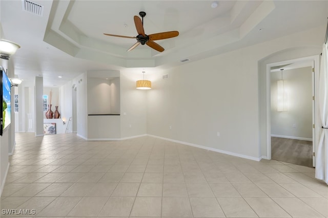 tiled spare room featuring ceiling fan and a tray ceiling