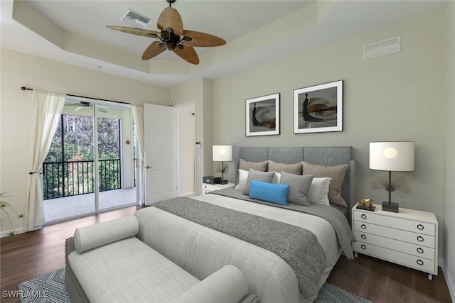 bedroom with ceiling fan, access to exterior, a raised ceiling, and dark hardwood / wood-style flooring