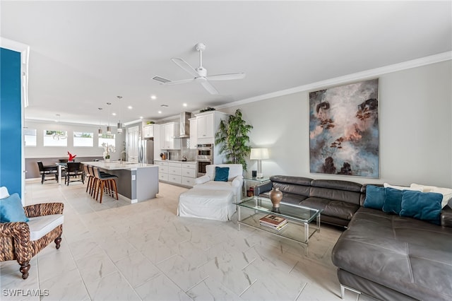 living room with ceiling fan, sink, and crown molding