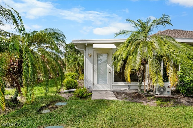 property entrance featuring a lawn and ac unit